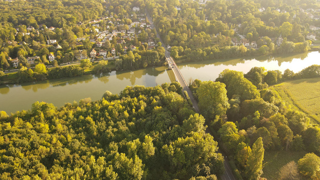 Aerial view of the Seine river and bridge surrounded by dense forests and residential houses in Chartrettes Ile de France France. Aerial view of the Seine river and bridge surrounded by dense forests and residential houses in Chartrettes Ile de France France.