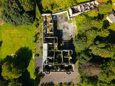 Aerial view of an abandoned and ruined building overgrown with vegetation surrounded by lush green trees and grass in Lisburn Northern Ireland United Kingdom. Aerial view of an abandoned and ruined building overgrown with vegetation surrounded by lush green trees and grass in Lisburn Northern Ireland United Kingdom.