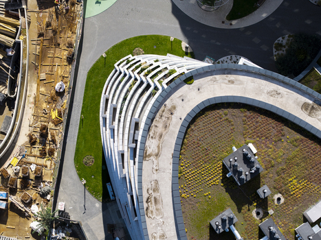 Aerial view of modern building with curved layered balconies and green roof surrounded by urban construction site in Krakow Lesser Poland Poland.
