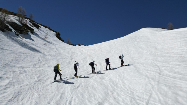 Aerial view of a group of ski tourers climbing the snowy slopes of Pointe Ronde under a clear blue sky in Trient Valais Switzerland.