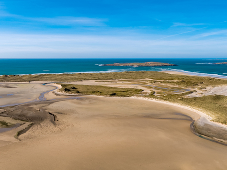 Aerial view of Ballyness Bay featuring expansive sandy tidal flats rolling green dunes and the Atlantic Ocean under a clear blue sky in Ballyness County Donegal Ireland. Aerial view of Ballyness Bay featuring expansive sandy tidal flats rolling green dunes and the Atlantic Ocean under a clear blue sky in Ballyness County Donegal Ireland.