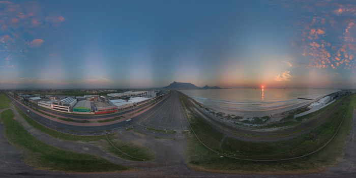 Aerial view of Table Mountain at sunset overlooking the coastline industrial buildings and coastal road in Cape Town Western Cape South Africa.