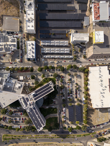 Aerial view of solar panels installed on rooftops and parking structures in an urban area with surrounding roads and buildings Chihuahua Chihuahua Mexico. Aerial view of solar panels installed on rooftops and parking structures in an urban area with surrounding roads and buildings Chihuahua Chihuahua Mexico.