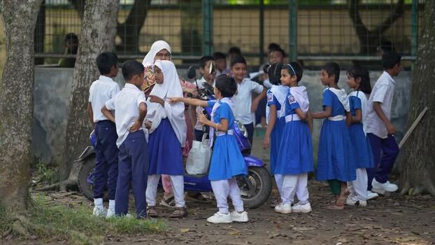 View of school children in uniforms near a motorcycle Bangladesh.