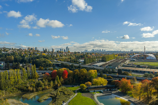 Aerial view of Vancouver Harbour with the city skyline in the distance surrounded by lush autumn foliage a highway and parkland in Vancouver British Columbia Canada. Aerial view of Vancouver Harbour with the city skyline in the distance surrounded by lush autumn foliage a highway and parkland in Vancouver British Columbia Canada.