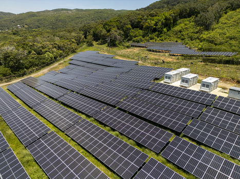 Aerial view of a large solar panel array nestled against lush green tropical hills under a clear blue sky Guanaja Bay Islands Department Honduras.