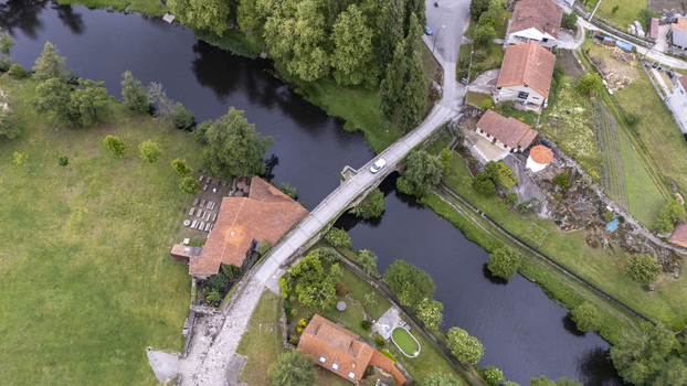 Aerial view of Ponte de Vilanova stone bridge crossing the Arnoia River surrounded by historic houses and lush green gardens in Allariz Ourense Spain. Aerial view of Ponte de Vilanova stone bridge crossing the Arnoia River surrounded by historic houses and lush green gardens in Allariz Ourense Spain.