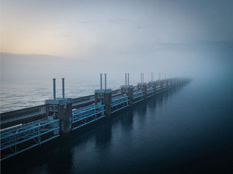 Aerial view of the Delta Projects Netherlands storm surge barrier with massive pillars and gates disappearing into thick fog over the sea in Vrouwenpolder Zeeland Netherlands.