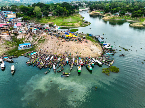 Rangamati Hill District Bangladesh 18 May 2024 Aerial view of Kaptai Lake with wooden boats docked at the shoreline bustling market activity and hillside buildings.