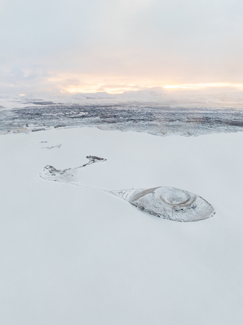 Aerial view of Myvatn lake with its volcanic crater island surrounded by vast snow covered landscape under a soft winter sky in Thingeyjarsveit Iceland. Aerial view of Myvatn lake with its volcanic crater island surrounded by vast snow covered landscape under a soft winter sky in Thingeyjarsveit Iceland.