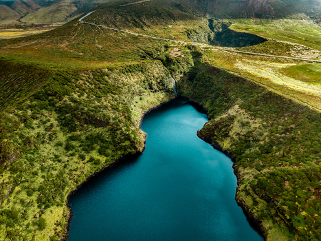 Aerial view of the deep blue lake embraced by rugged verdant hills and cliffs under the open sky Lake Comprida Flores Azores Portugal.