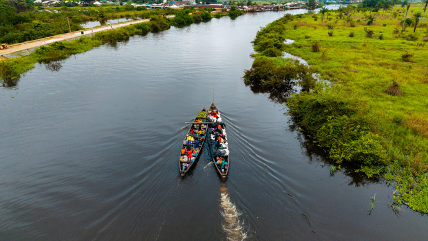 Aerial view of two wooden boats filled with people and goods navigating a river through lush green vegetation in Itu Akwa Ibom Nigeria. Aerial view of two wooden boats filled with people and goods navigating a river through lush green vegetation in Itu Akwa Ibom Nigeria.