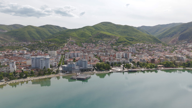 Aerial view of the coastal town of Pogradec with its urban architecture hotels and promenade along the calm waters of Lake Ohrid Pogradec Korce County Albania. Aerial view of the coastal town of Pogradec with its urban architecture hotels and promenade along the calm waters of Lake Ohrid Pogradec Korce County Albania.