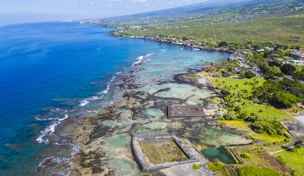 Aerial view of Kahalu u Beach Park featuring ancient stone structures and turquoise coral reefs along the volcanic coastline in Kailua Kona Hawaii United States. Aerial view of Kahalu u Beach Park featuring ancient stone structures and turquoise coral reefs along the volcanic coastline in Kailua Kona Hawaii United States.