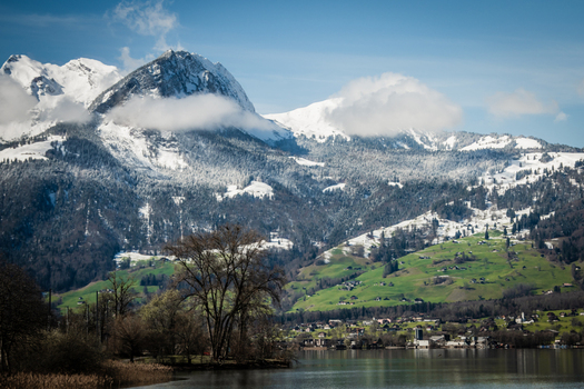View of the majestic snow capped Alps towering over the tranquil lake and verdant landscape from the train Train from Lucerne to Interlaken Switzerland. View of the majestic snow capped Alps towering over the tranquil lake and verdant landscape from the train Train from Lucerne to Interlaken Switzerland.