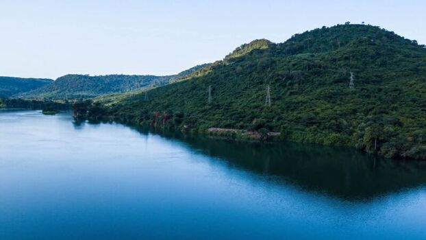 Aerial view of a calm river winding through lush green hills and dense vegetation in Ghana. Aerial view of a calm river winding through lush green hills and dense vegetation in Ghana.
