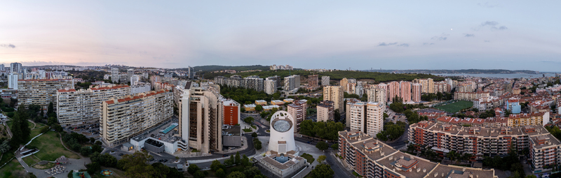 Aerial view of the urban landscape of Alges featuring modern residential buildings a distinctive white architectural structure and lush green spaces in Alges Lisbon Portugal.