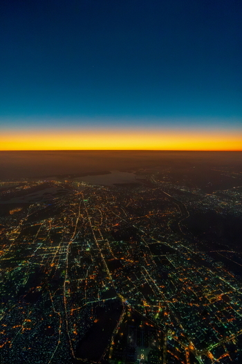 Aerial view of the sprawling city lights of Karachi at dusk with a vibrant sunset horizon in Karachi Sindh Pakistan.