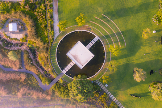 Aerial view of a modern square pavilion centered in a circular pond surrounded by lush landscaped gardens and green lawns in Cape Town Western Cape South Africa. Aerial view of a modern square pavilion centered in a circular pond surrounded by lush landscaped gardens and green lawns in Cape Town Western Cape South Africa.