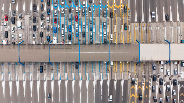 Aerial view of the Milano Sud toll plaza on the A1 motorway showing lanes with vehicles passing through toll gates highway infrastructure and road markings in Melegnano Lombardy Italy.