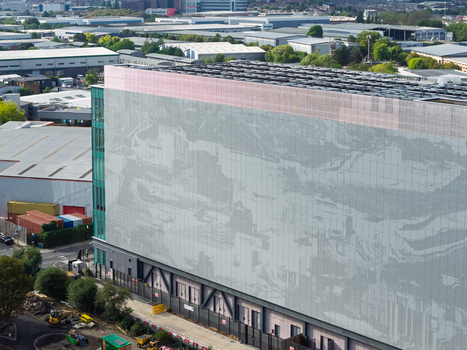Aerial view of a modern data center building featuring a large patterned facade and glass elements situated within an industrial park United Kingdom. Aerial view of a modern data center building featuring a large patterned facade and glass elements situated within an industrial park United Kingdom.