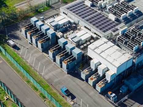 Aerial view of a data center facility with industrial cooling units rooftop solar panels and a paved parking area United Kingdom.