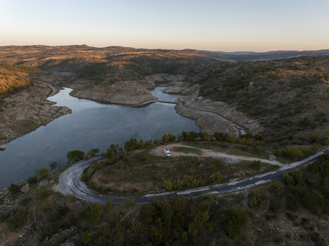 Aerial view of a winding road and a parked camper van overlooking a reservoir surrounded by rolling hills during golden hour in Kirklareli Merkez Kirklareli Turkey. Aerial view of a winding road and a parked camper van overlooking a reservoir surrounded by rolling hills during golden hour in Kirklareli Merkez Kirklareli Turkey.