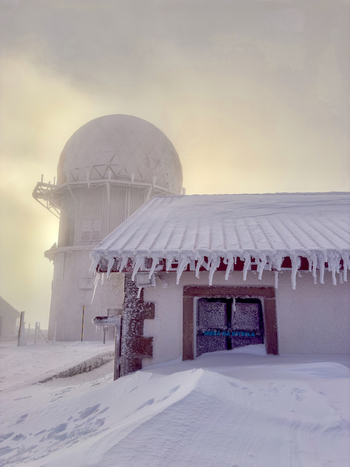 View of an icy landscape where a building stands blanketed in snow with a dome structure shrouded in mist creating a serene yet cold atmosphere Covilh&atilde; Distrito da Guarda Portugal.