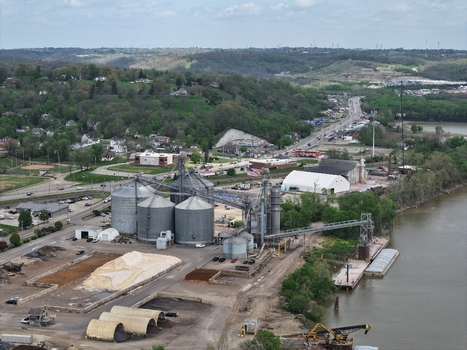 Aerial view of industrial grain silos and storage facilities along the riverbank with rolling green hills Aurora Indiana United States. Aerial view of industrial grain silos and storage facilities along the riverbank with rolling green hills Aurora Indiana United States.