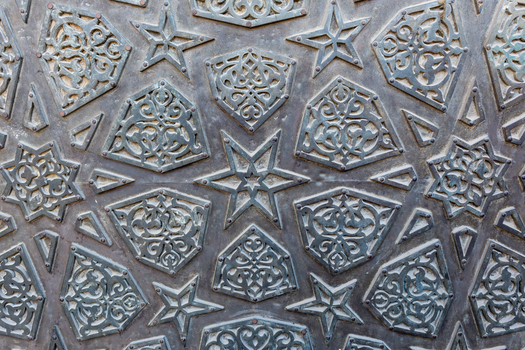 View of intricate geometric patterns and arabesque carvings on the historic metal door at the Mosque of al Salih Tala i Cairo Egypt. View of intricate geometric patterns and arabesque carvings on the historic metal door at the Mosque of al Salih Tala i Cairo Egypt.
