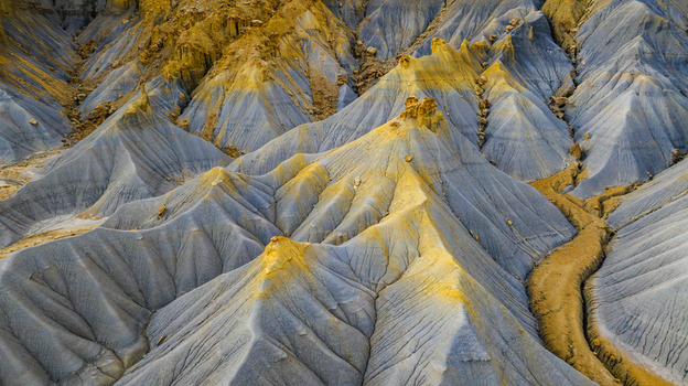 Aerial view of badlands with colorful eroded clay hills intricate ridges and dry drainage channels in Hanksville Utah United States.