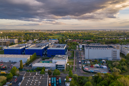 Aerial view of the Digital Realty Frankfurt FRA30 data center complex with large blue buildings and surrounding greenery under a cloudy sunset sky in Frankfurt am Main Hessen Germany. Aerial view of the Digital Realty Frankfurt FRA30 data center complex with large blue buildings and surrounding greenery under a cloudy sunset sky in Frankfurt am Main Hessen Germany.