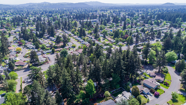 Aerial view of Northeast Glisan Street passing through a green suburban neighborhood with tall evergreen trees and residential houses Portland Oregon United States. Aerial view of Northeast Glisan Street passing through a green suburban neighborhood with tall evergreen trees and residential houses Portland Oregon United States.