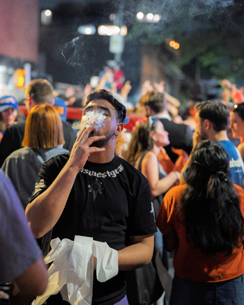 Williamsburg Brooklyn New York USA 14 June 2026 View of a man smoking a cigarette amidst a vibrant crowd during celebrations in the street at night. Williamsburg Brooklyn New York USA 14 June 2026 View of a man smoking a cigarette amidst a vibrant crowd during celebrations in the street at night.