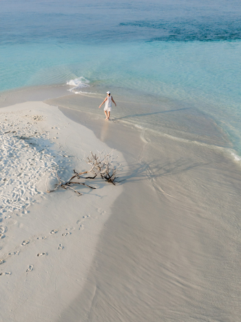 Aerial view of a person walking on the pristine white sands contrasting with the turquoise sea Dhidhdhoo Thiladhunmathi Atoll Maldives.