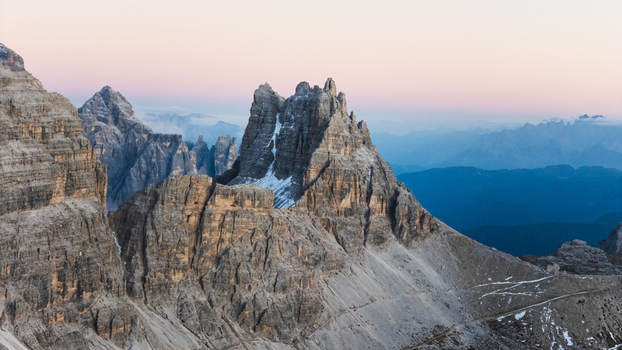 Aerial view of the iconic Tre Cime di Lavaredo peaks with jagged rock formations and steep cliffs under a soft twilight sky Auronzo di Cadore Veneto Italy. Aerial view of the iconic Tre Cime di Lavaredo peaks with jagged rock formations and steep cliffs under a soft twilight sky Auronzo di Cadore Veneto Italy.