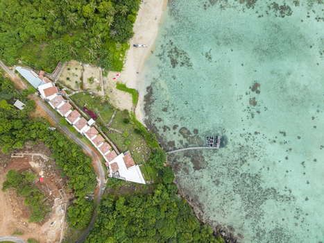 Aerial view of the Cottage Legon Waru nestled amidst lush greenery where the turquoise waters meet the sandy shore Karimunjawa Central Java Indonesia.