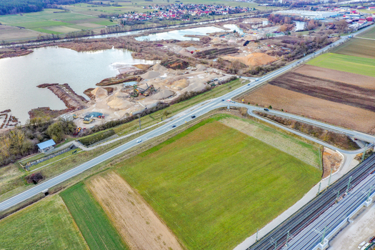 Aerial view of a gravel quarry with sand piles and water ponds next to a road and railway tracks surrounded by agricultural fields Forchheim Bavaria Germany. Aerial view of a gravel quarry with sand piles and water ponds next to a road and railway tracks surrounded by agricultural fields Forchheim Bavaria Germany.