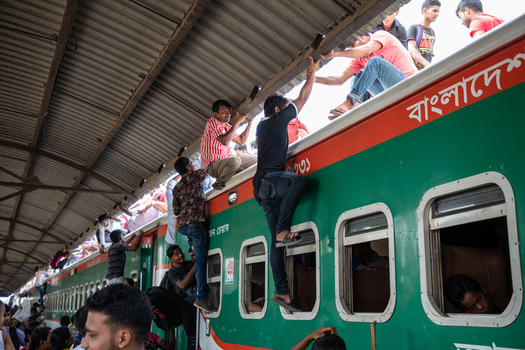 Dhaka Bangladesh 14 June 2018 View of people climbing onto the roof of a crowded train at Airport Railway Station during the Eid al Fitr holiday rush. Dhaka Bangladesh 14 June 2018 View of people climbing onto the roof of a crowded train at Airport Railway Station during the Eid al Fitr holiday rush.