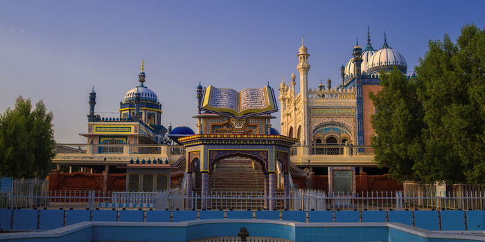 View of the ornate Jamia Masjid Bhong Sharif with its intricate tile work domes and a central structure resembling an open book in Bhong Punjab Pakistan.