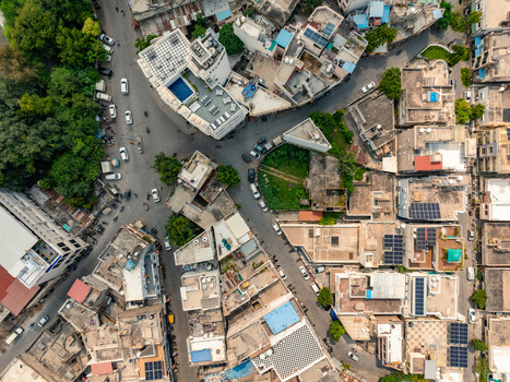 Aerial view of the dense urban fabric featuring traditional buildings narrow streets solar panels on rooftops and a small green courtyard in Udaipur Rajasthan India. Aerial view of the dense urban fabric featuring traditional buildings narrow streets solar panels on rooftops and a small green courtyard in Udaipur Rajasthan India.