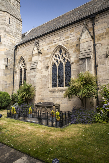 View of the historic stone exterior and gothic windows of St. Andrew s Church with a stone tomb in the foreground Newcastle upon Tyne England United Kingdom. View of the historic stone exterior and gothic windows of St. Andrew s Church with a stone tomb in the foreground Newcastle upon Tyne England United Kingdom.