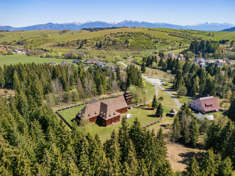 Aerial view of the Wooden Articular Church of Svaty Kriz surrounded by lush evergreen forests and rolling hills with mountains in the distance Svaty Kriz Zilinsky kraj Slovakia.