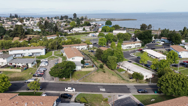 Aerial view of the residential neighborhood featuring low rise buildings tree lined streets and parked cars situated along the coastline in Rodeo California United States.