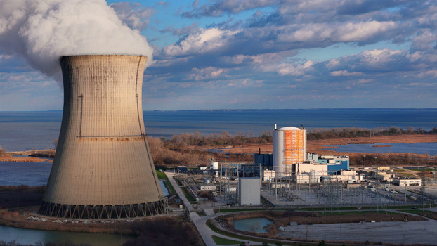 Aerial view of Davis Besse Nuclear Power Station with its cooling tower emitting steam situated near the shoreline in Oak Harbor Ohio United States.