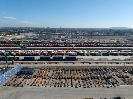 Aerial view of an intermodal rail yard with rows of colorful shipping containers rail cars and chassis trailers in the industrial landscape of Carson California United States.