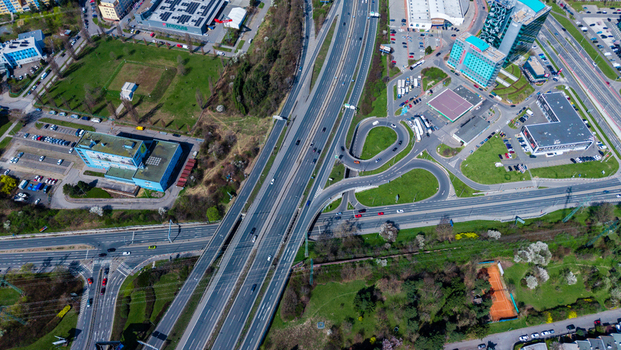 Aerial view of a highway interchange cutting through green spaces and connecting buildings with cars moving along the roads Prague Prague Czechia. Aerial view of a highway interchange cutting through green spaces and connecting buildings with cars moving along the roads Prague Prague Czechia.