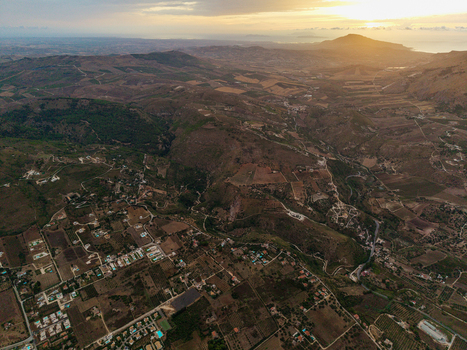 Aerial view of rolling hills and agricultural fields with scattered residential houses under a warm sunset sky in the countryside Palermo Sicily Italy. Aerial view of rolling hills and agricultural fields with scattered residential houses under a warm sunset sky in the countryside Palermo Sicily Italy.