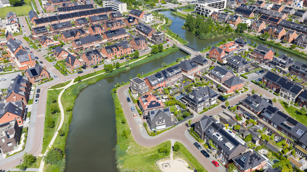 Aerial view of a modern residential neighborhood in Utrecht featuring rows of brick houses with solar panels a winding canal and green pathways in Utrecht Utrecht Netherlands. Aerial view of a modern residential neighborhood in Utrecht featuring rows of brick houses with solar panels a winding canal and green pathways in Utrecht Utrecht Netherlands.