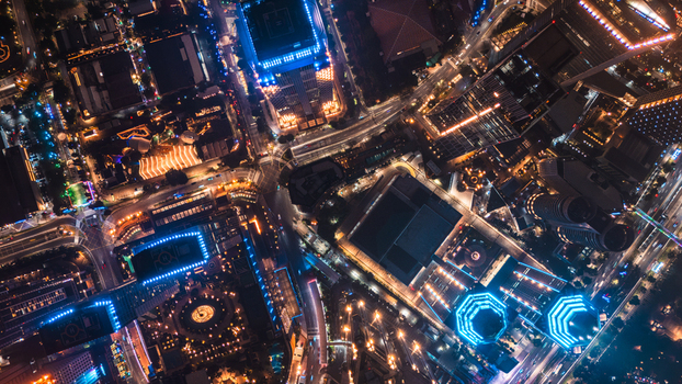 Aerial view of the illuminated city streets and skyscrapers of Jakarta at night featuring glowing building lights busy traffic patterns and modern urban architecture in Jakarta Indonesia.